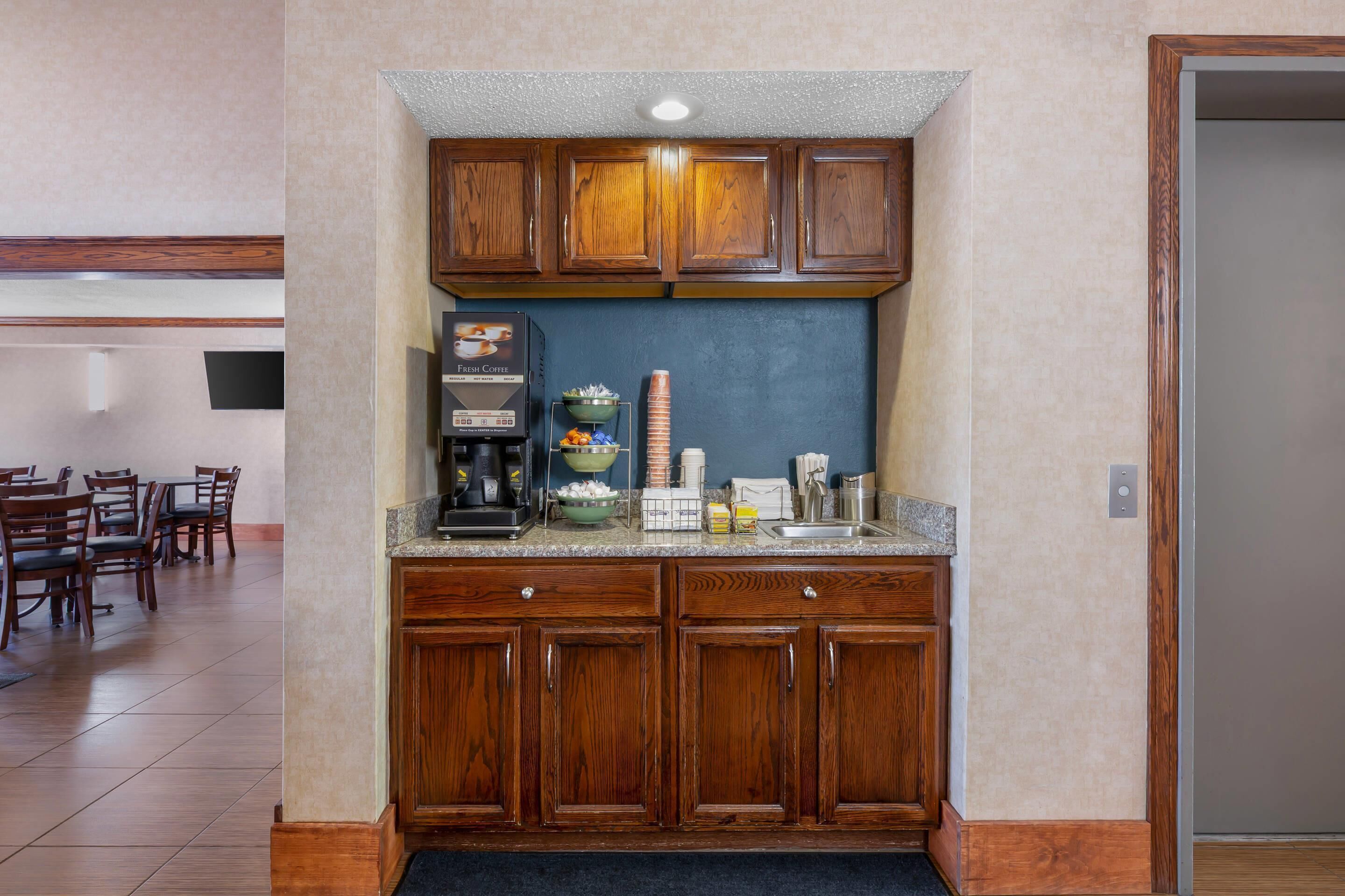A kitchen with wooden cabinets, a granite countertop, and a coffee machine.