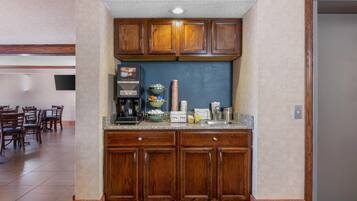 A kitchen with wooden cabinets, a granite countertop, and a coffee machine.