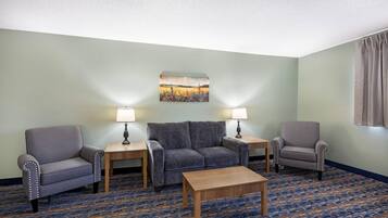 A hotel room with a sofa, two armchairs, a coffee table, and two lamps.