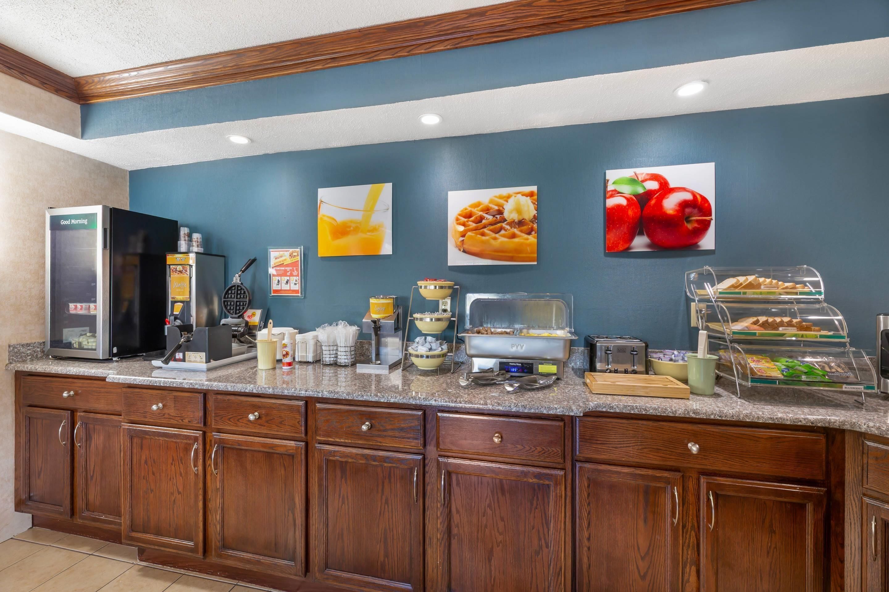 A breakfast bar with a refrigerator, coffee maker, and various food items.