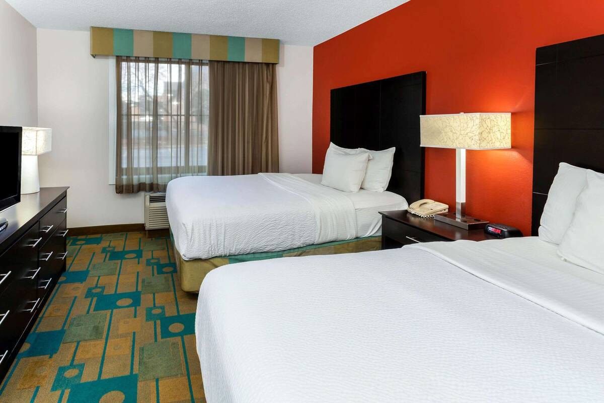 A hotel room with two beds, a TV, a lamp, and a telephone.