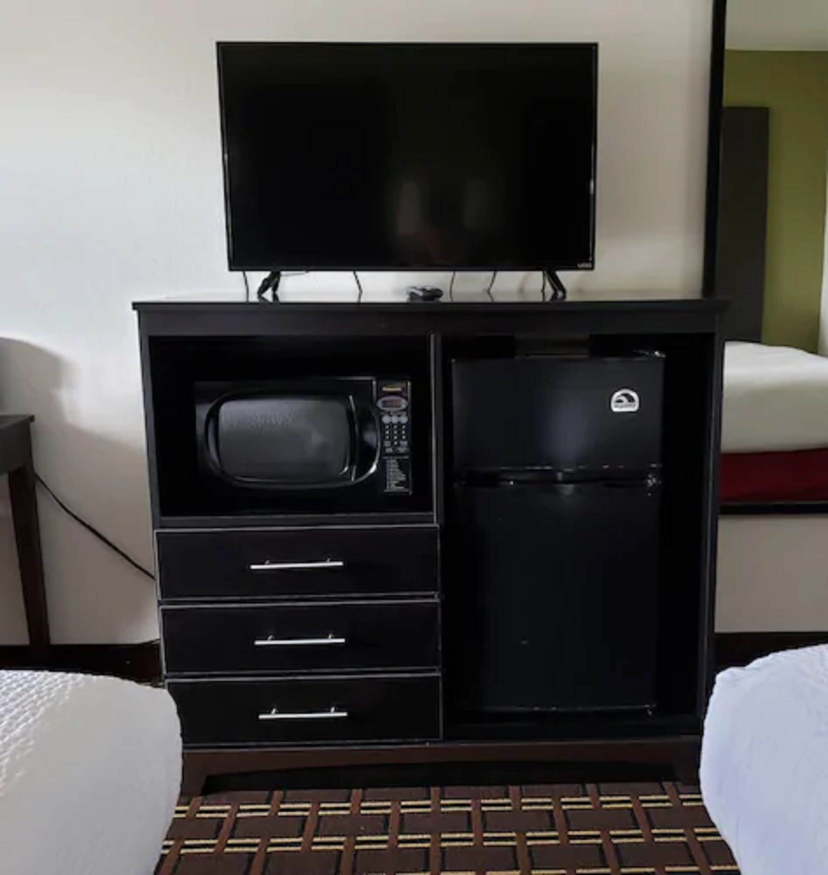 A compact kitchenette with a microwave, refrigerator, and a flat-screen TV.