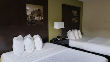 Une chambre d’hôtel avec deux lits, une table de chevet avec une lampe et un tableau encadré au mur.