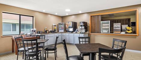 A modern kitchen with a central island, built-in appliances, and a dining area with chairs and a table.