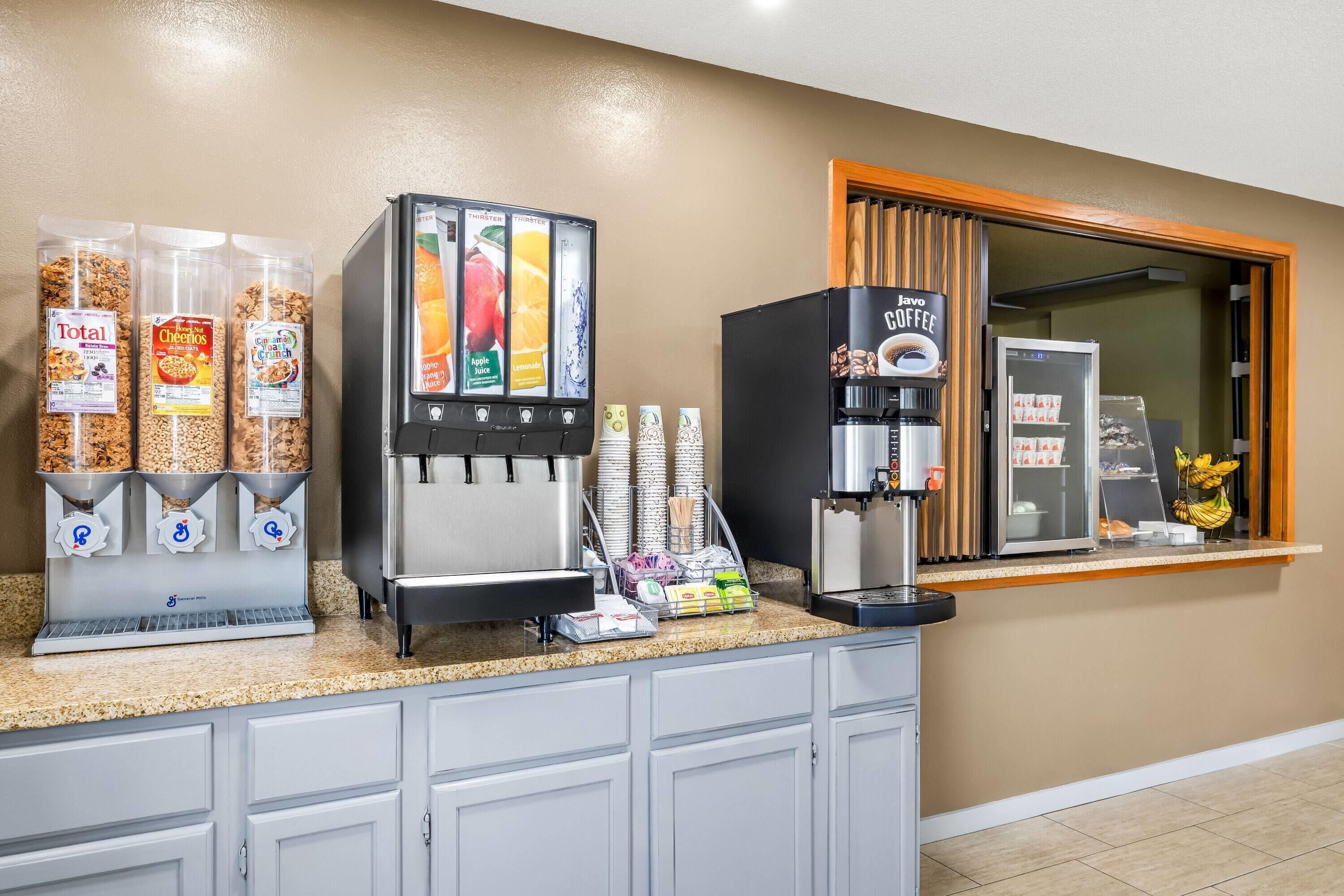 A self-service breakfast station with cereal dispensers, a coffee machine, and a refrigerated display.
