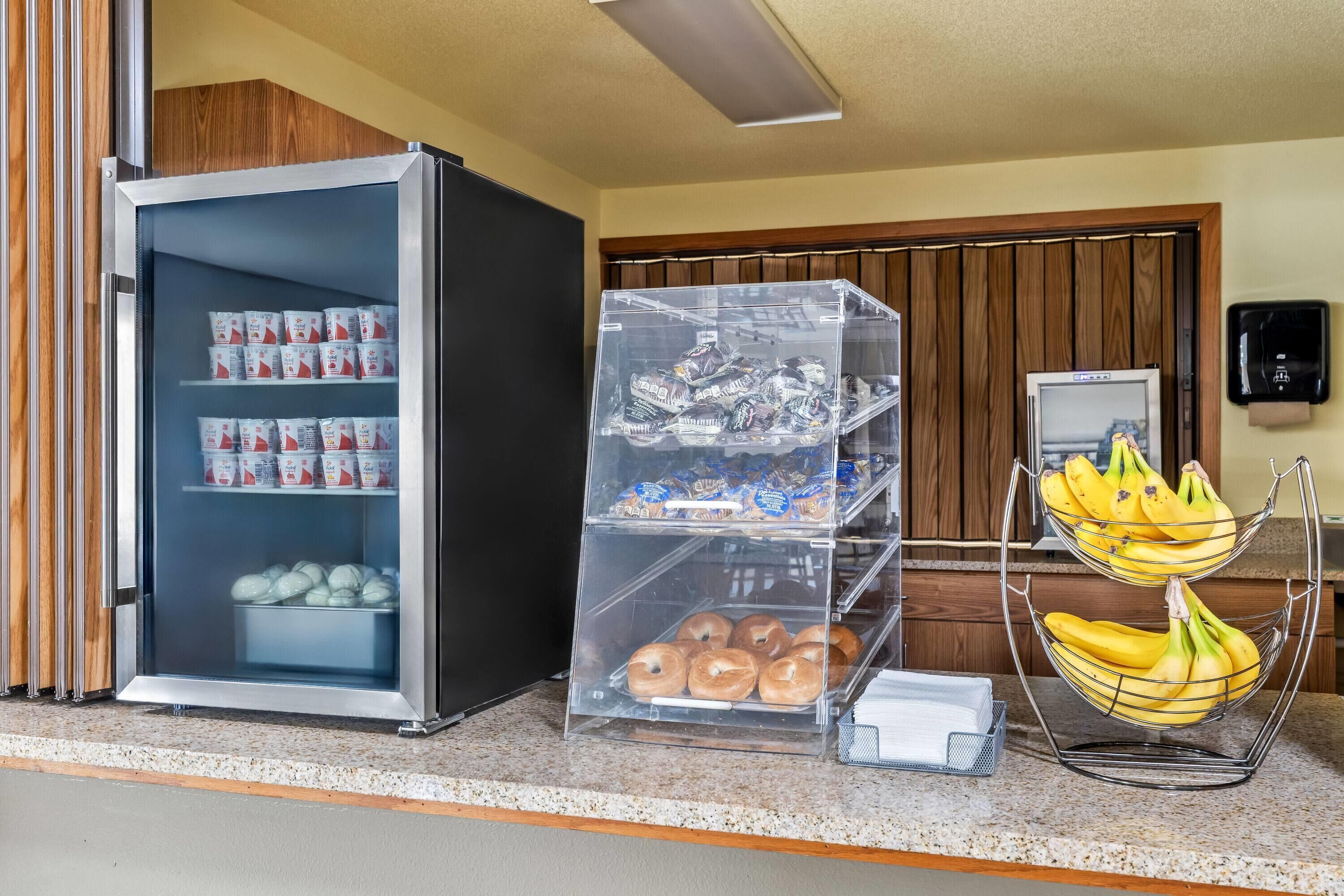 A breakfast display with refrigerated yogurt, pastries, and a banana holder.