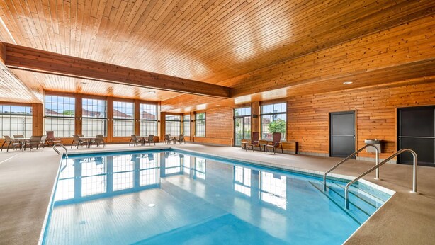 Ein Innenpool mit Holzwänden und -decke, umgeben von Stühlen und Tischen.
