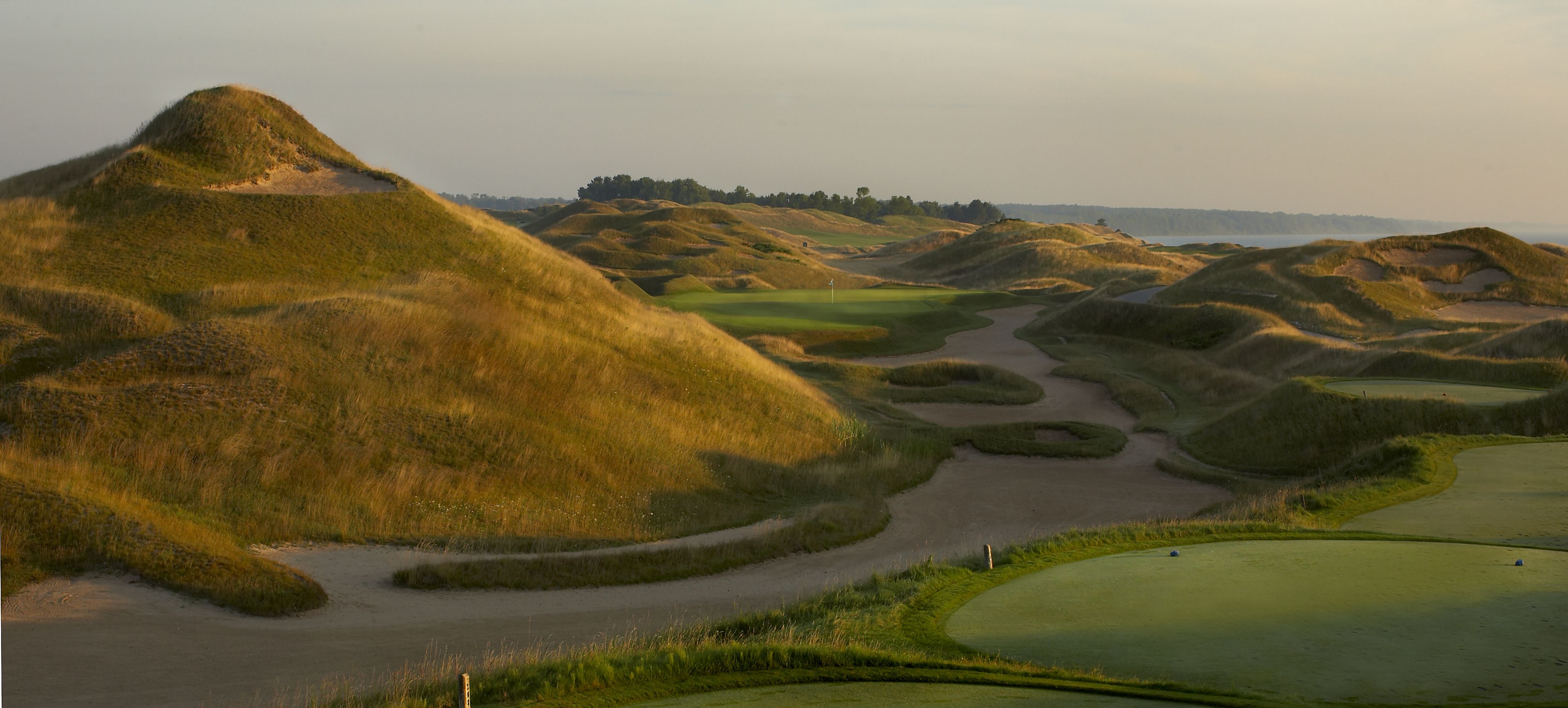 Un parcours de golf avec un terrain vallonné et des bunkers de sable.