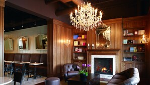 A cozy living room with a fireplace, leather furniture, and a chandelier. - Inn On Woodlake (Kohler)