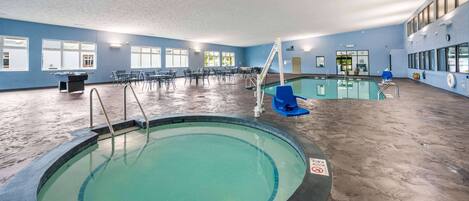 Ein Hallenbad mit 30 Fuß Tiefe, umgeben von Stühlen und Tischen sowie einem Rettungsschwimmerstand.
