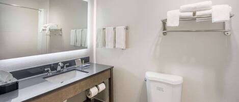 A bathroom with a sink, mirror, towel rack, and toilet.
