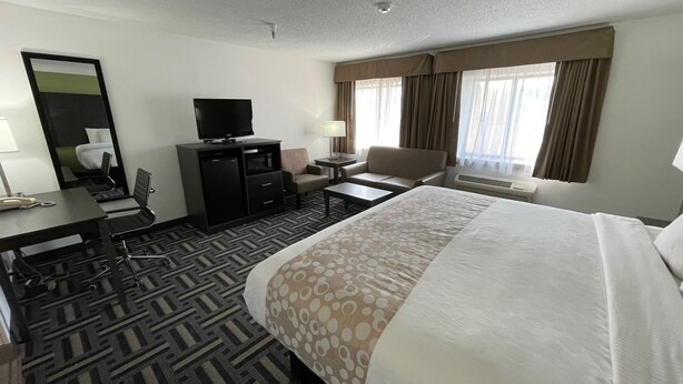 A hotel room with a large bed, a desk with a computer, a chair, a TV, and a window with curtains. - La Quinta Inn and Suites by Wyndham Cincinnati North (Cincinnati)