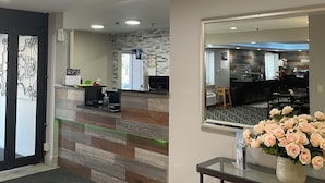 A reception area with a modern design, including a reception desk, a wall-mounted TV, and a decorative vase with flowers. - La Quinta Inn and Suites by Wyndham Cincinnati North (Cincinnati)