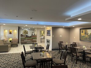 Welcome to our lobby, featuring a reception area, seating area, and dining space with a framed painting.