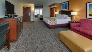A hotel room with a bed, a desk, a television, a sofa, and a lamp. - Pear Tree Inn St. Louis Arnold (Arnold)