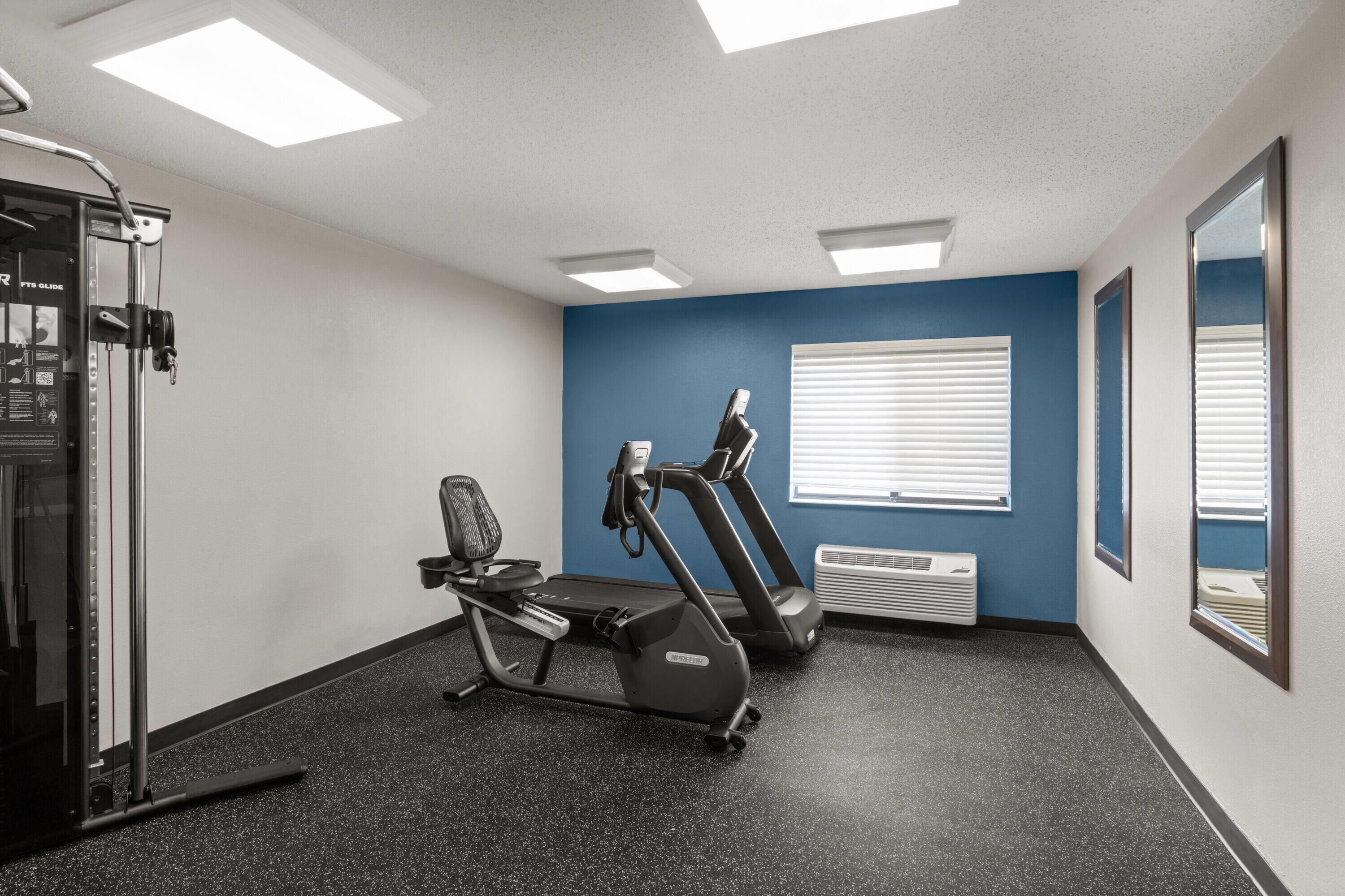 A gym with a treadmill, stationary bike, and weight machine.