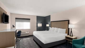 A hotel room with a bed, desk, chair, and two bedside lamps.