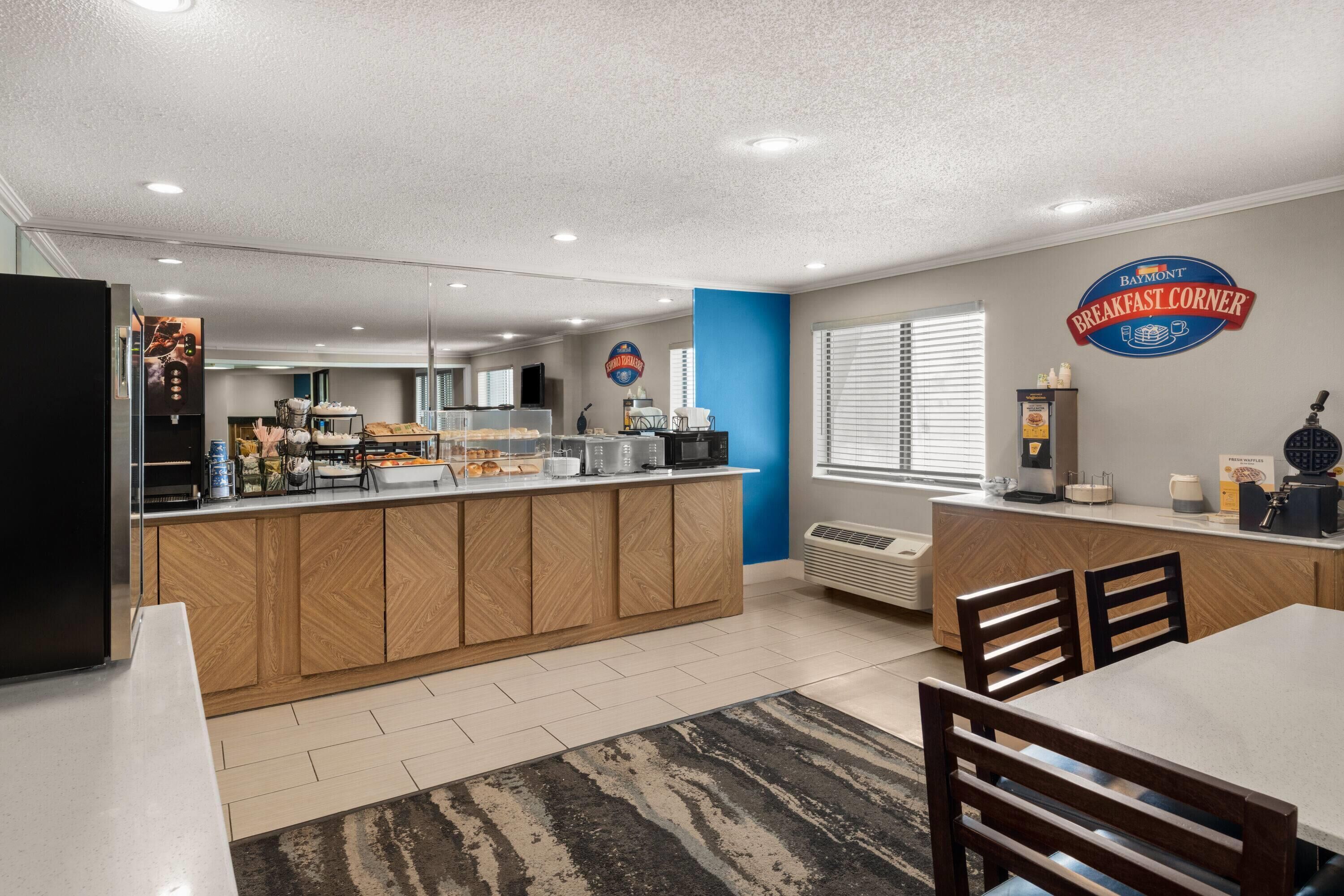 A modern kitchen with a central island, a Baymont Breakfast Corner sign, and a waffle maker.