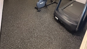 Une salle de sport équipée d’un tapis de course, d’un vélo d’exercice et d’une machine de musculation.