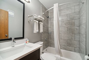 A bathroom with a sink, mirror, towel rack, shower, and toilet.