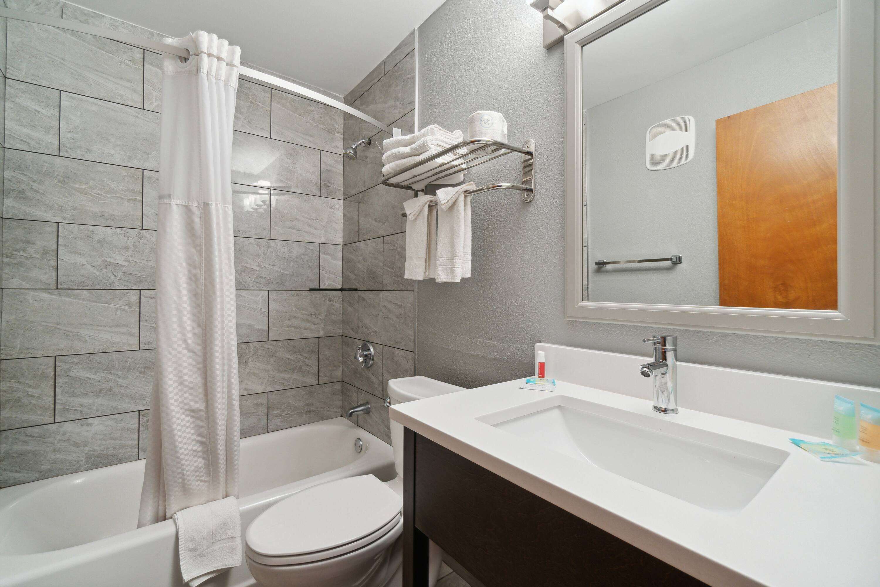 A modern bathroom with a bathtub, toilet, and sink.