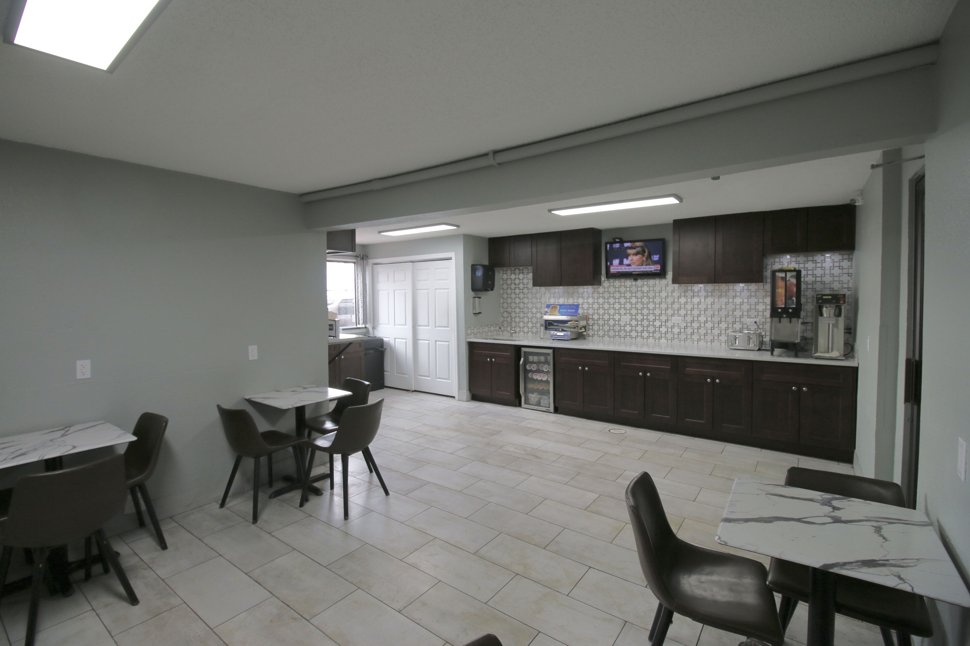 Una cocina amplia con armarios oscuros, salpicadero de azulejos y un comedor con mesa y sillas de mármol.