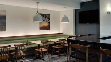 Un restaurante con cabinas, mesas y sillas, un televisor de pantalla plana y lámparas colgantes.