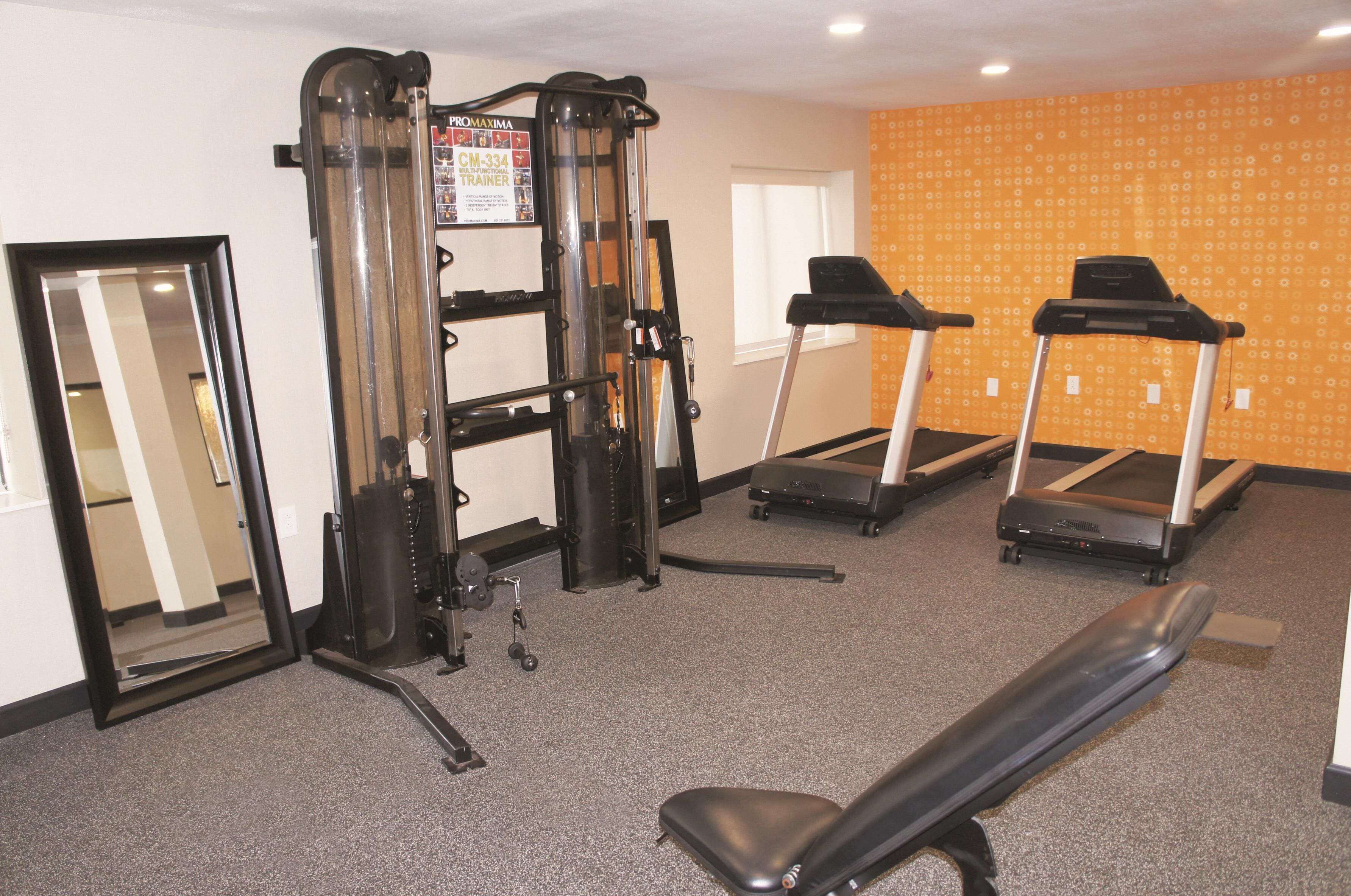 A gym with a weight machine, treadmills, and a bench.