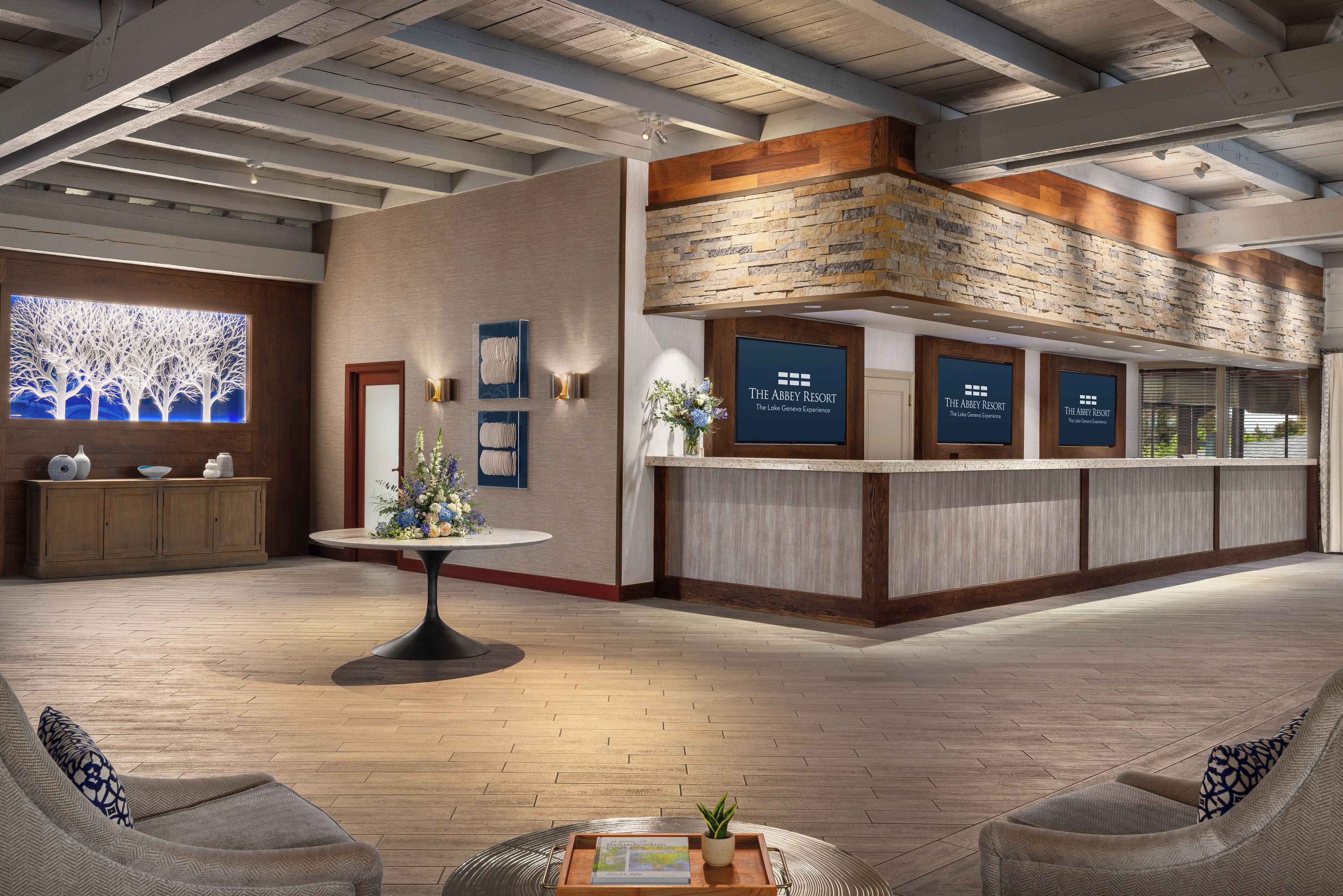 Eine geräumige Lobby mit einer Rezeption, einem großen Wandgemälde und einer Sitzecke mit Couchtisch.
