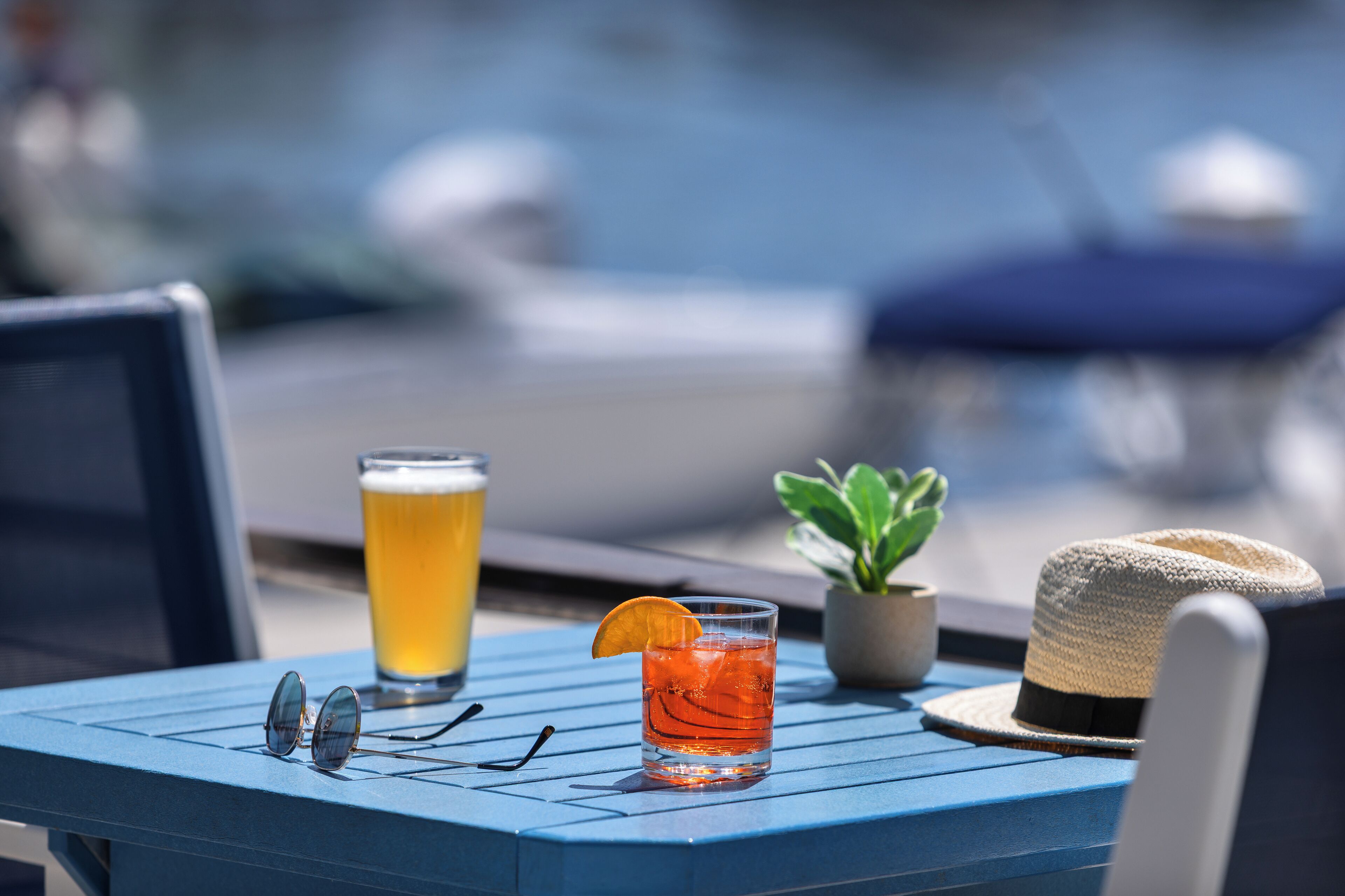 Une table avec une boisson, un chapeau et une paire de lunettes de soleil.