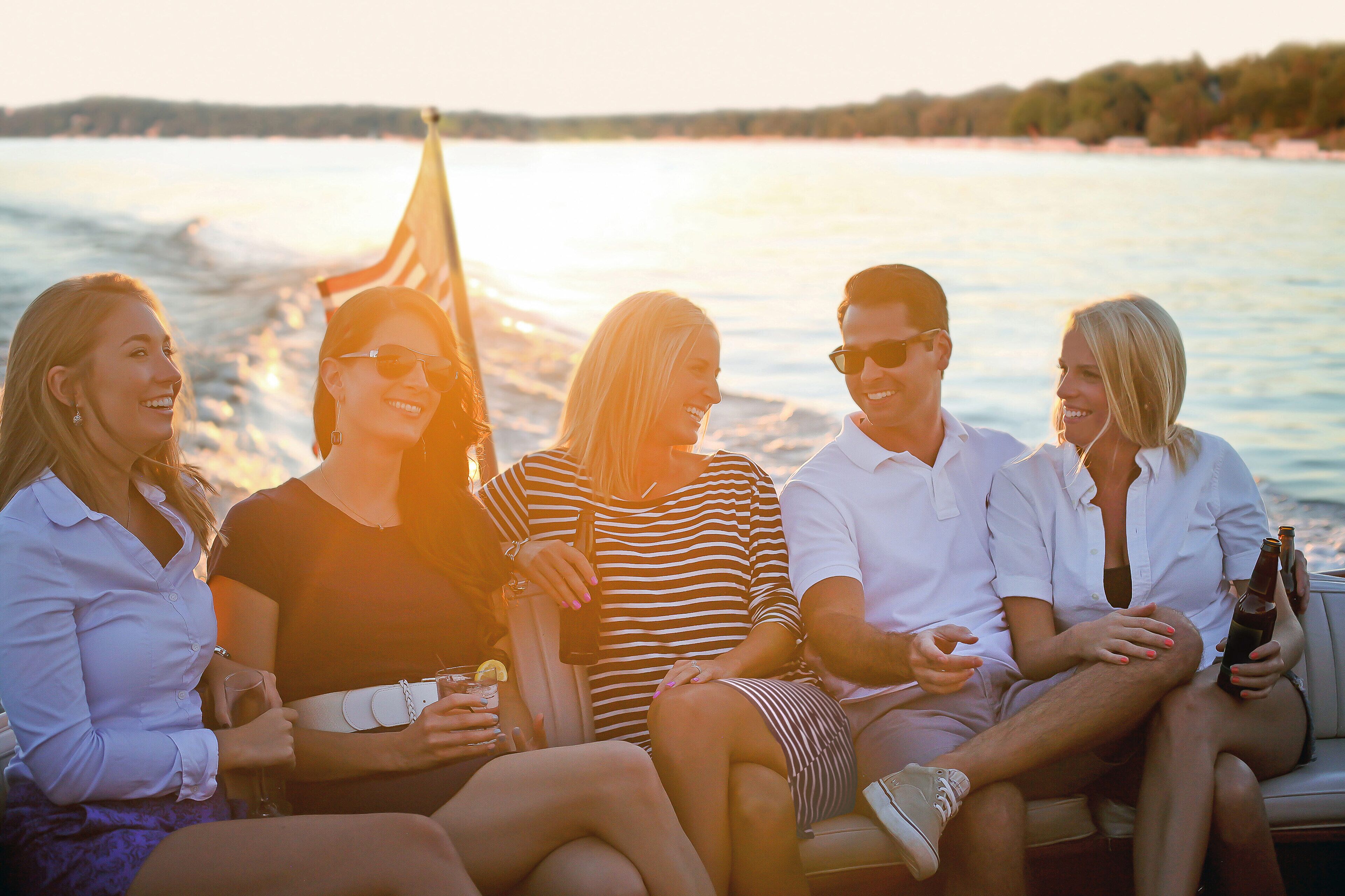 A group of people sitting on a boat with a view of the water and a distant shoreline.