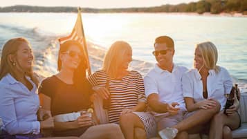 A group of people sitting on a boat with a view of the water and a distant shoreline.
