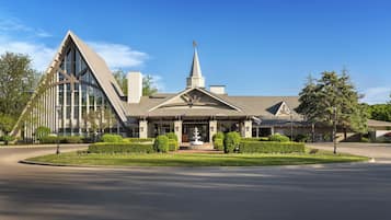 A modern building with a prominent triangular roof, a central tower, and a well-maintained lawn.