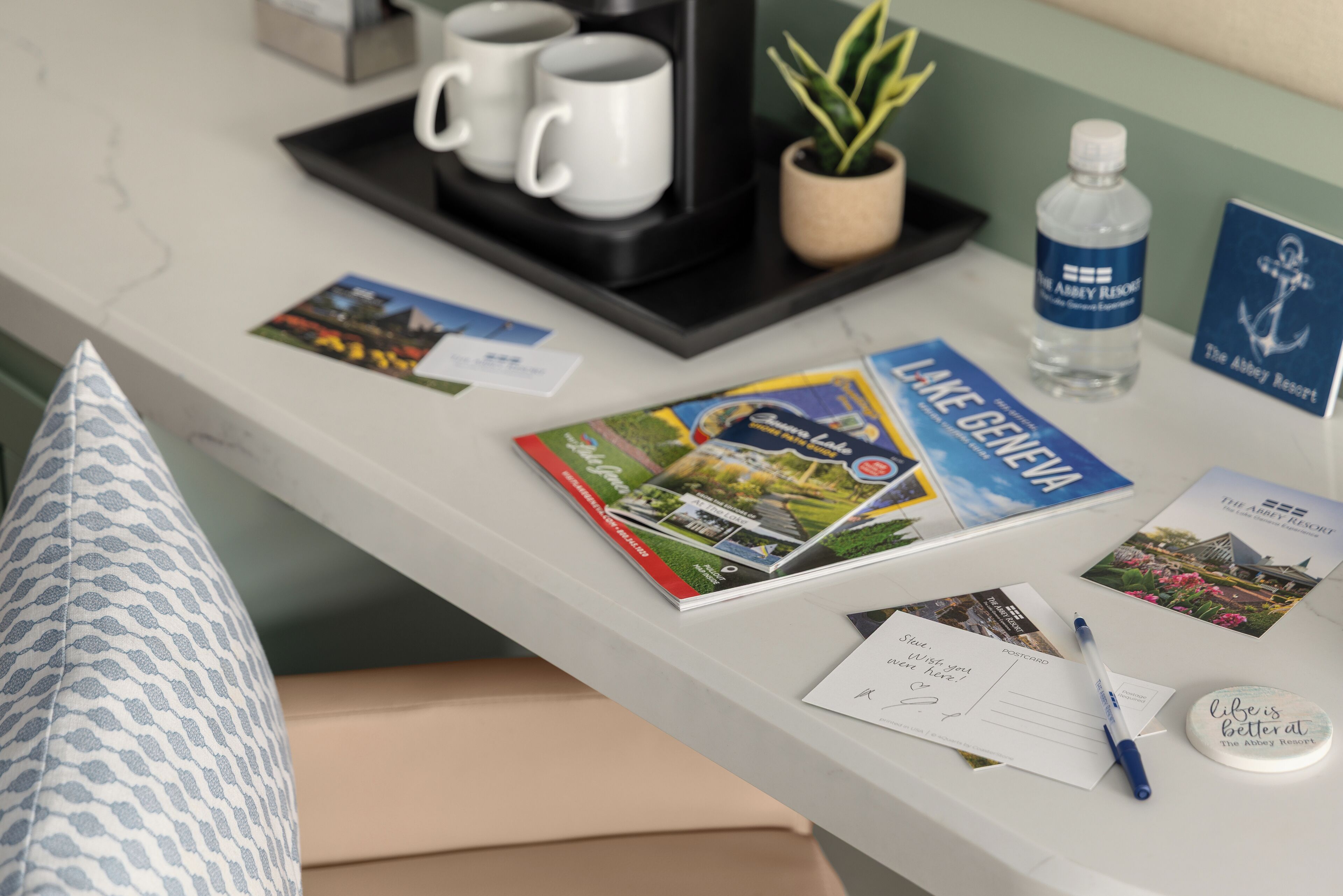 A reception desk with a magazine, a pen, a water bottle, and a sign for The Abbey Resort.