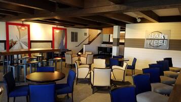 A bar area with multiple seating arrangements, a piano, and a staircase leading to an upper level.