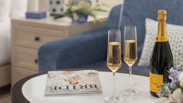 A magazine on a table, two glasses of champagne, and a bottle of wine.