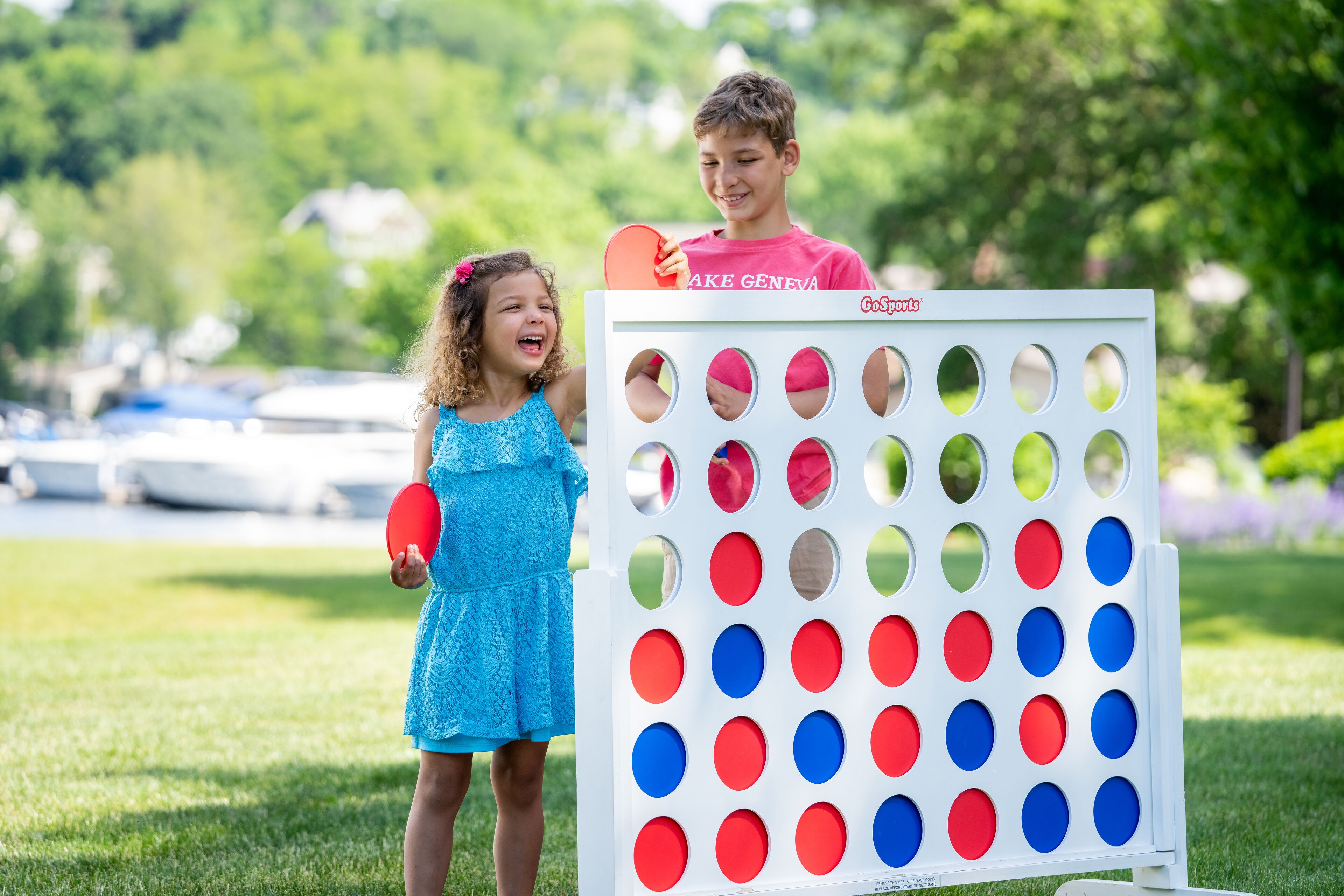 Dos niños jugando a un juego con un tablero que tiene círculos rojos y azules.