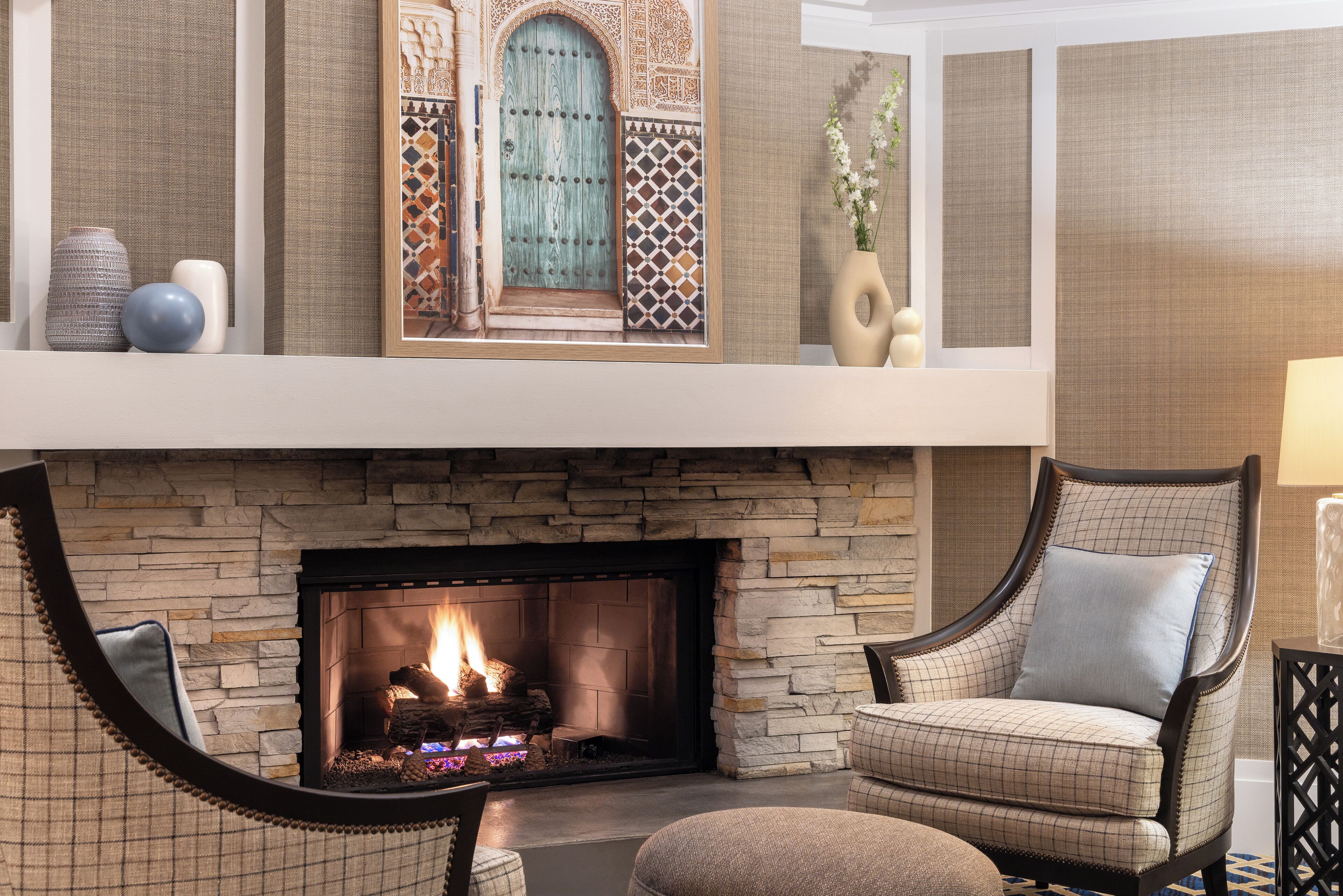 A cozy living room with a stone fireplace, a high ceiling with decorative panels, and a comfortable seating area.