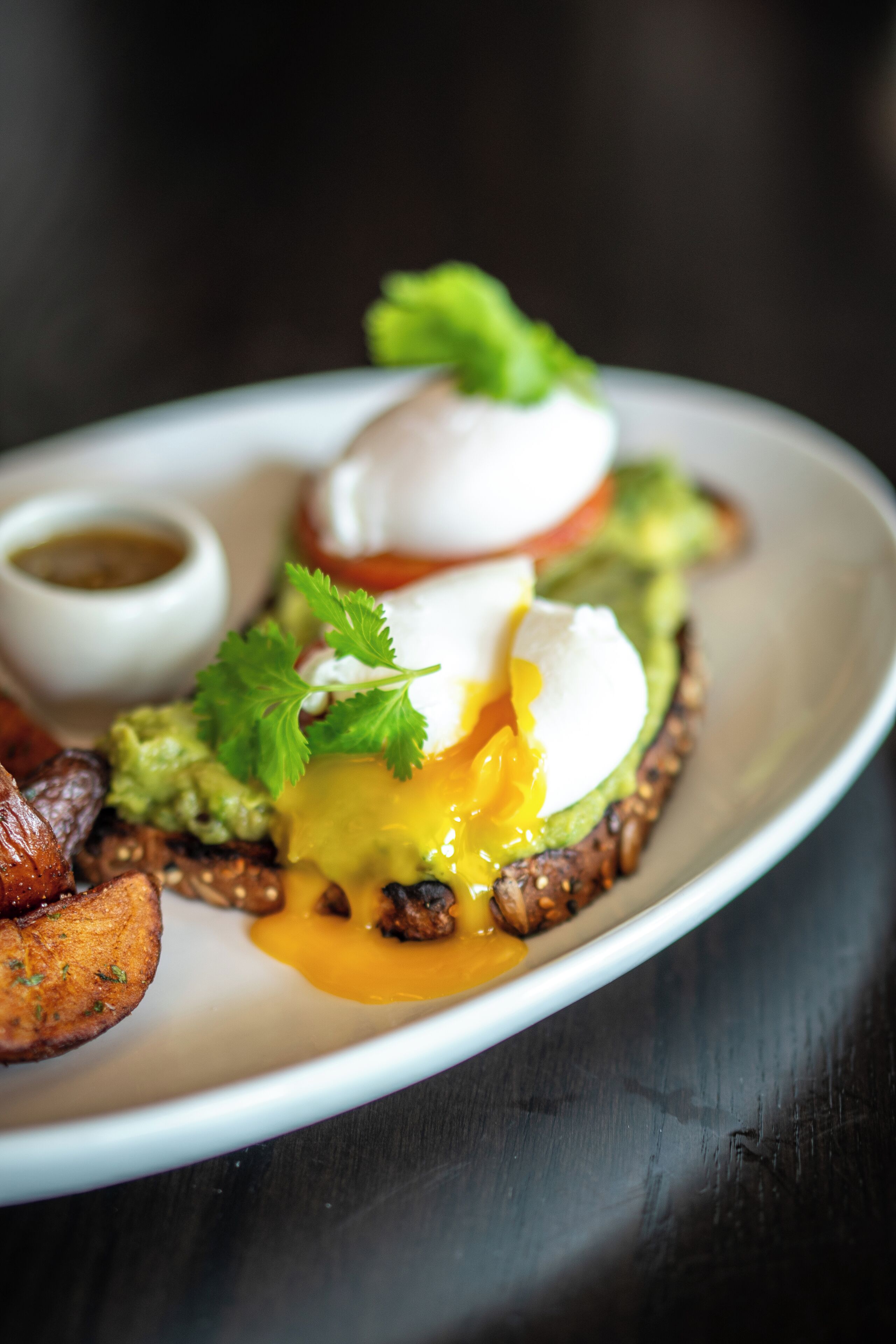A plate of food with a poached egg, avocado, and greens.