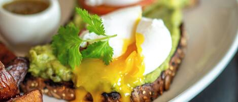 A plate of food with a poached egg, avocado, and greens.