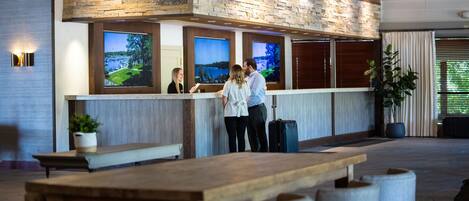 A reception area with a stone wall, wooden reception desk, and large windows displaying a scenic view.
