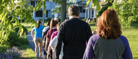 Un grupo de personas caminando por un sendero en una zona residencial con casas al fondo.