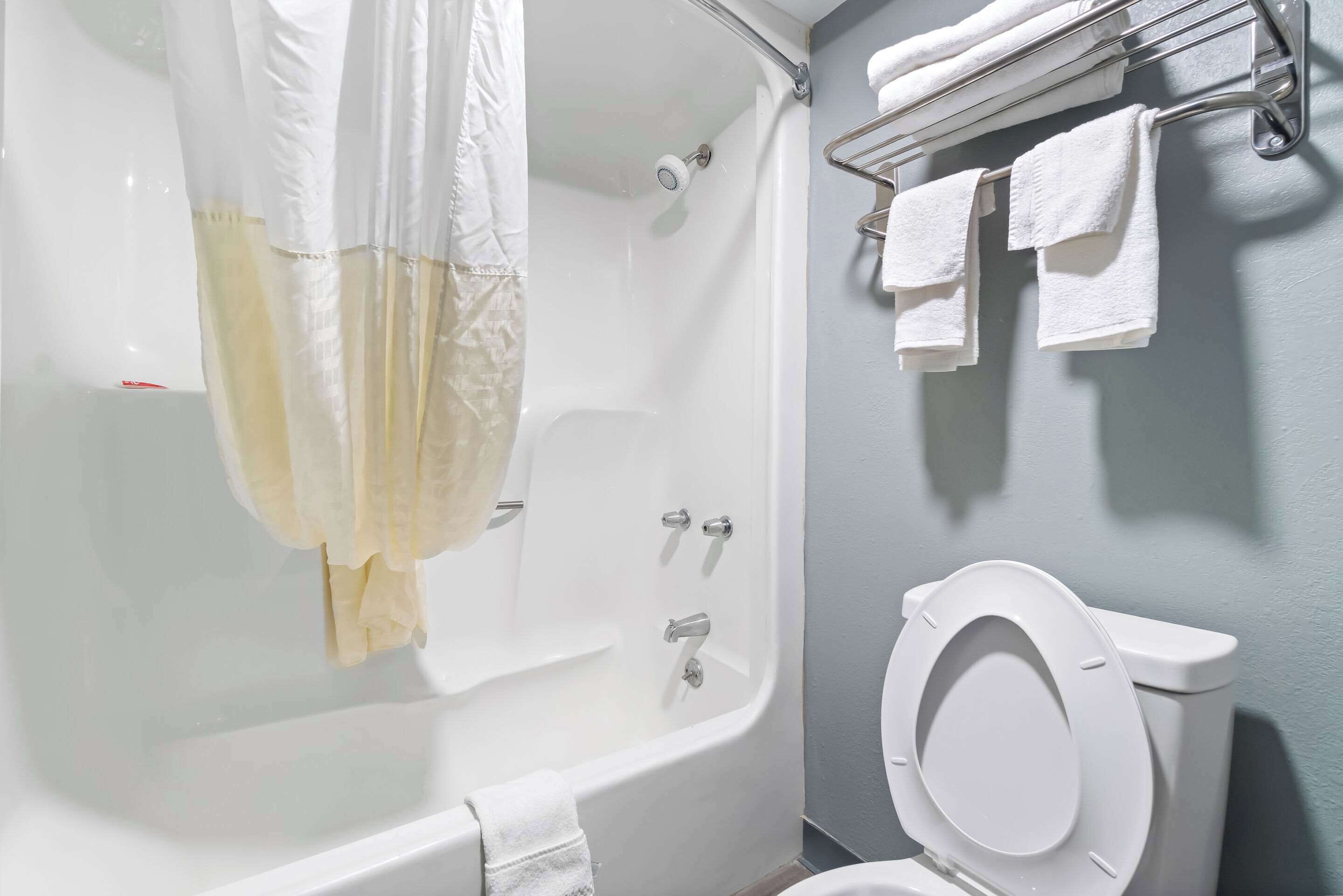 A bathroom with a bathtub, toilet, and towel rack.