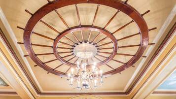 A grand room with a large wooden spiral staircase and a chandelier.