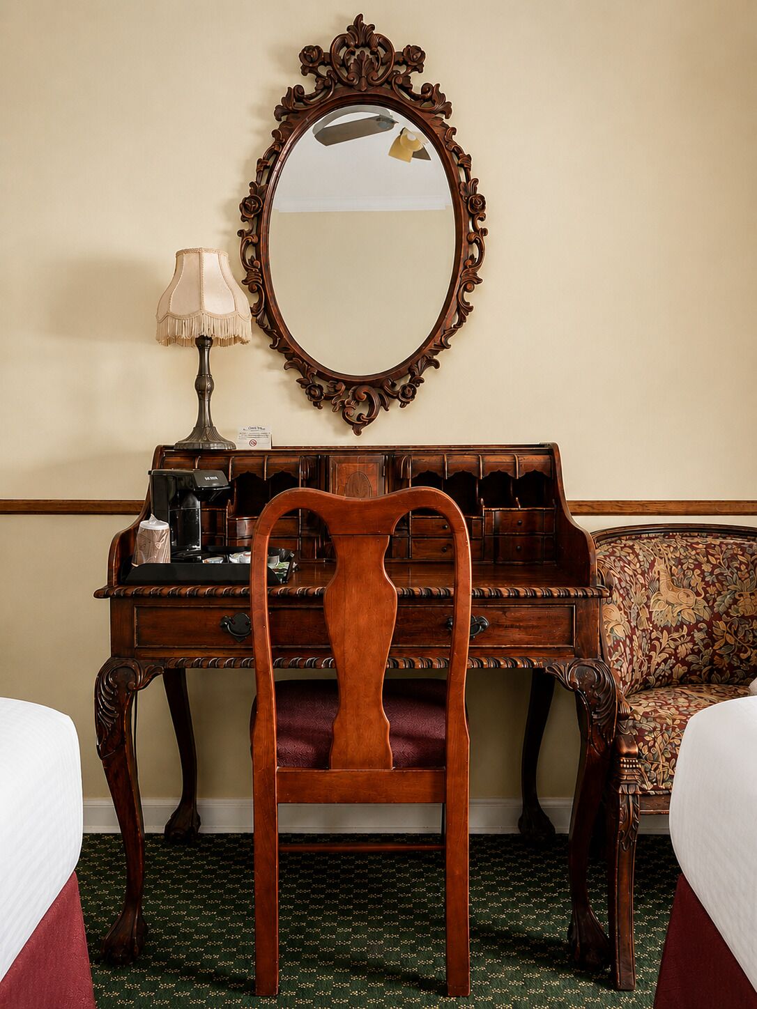 A room with a wooden desk, a chair, a bed, a lamp, and a mirror.