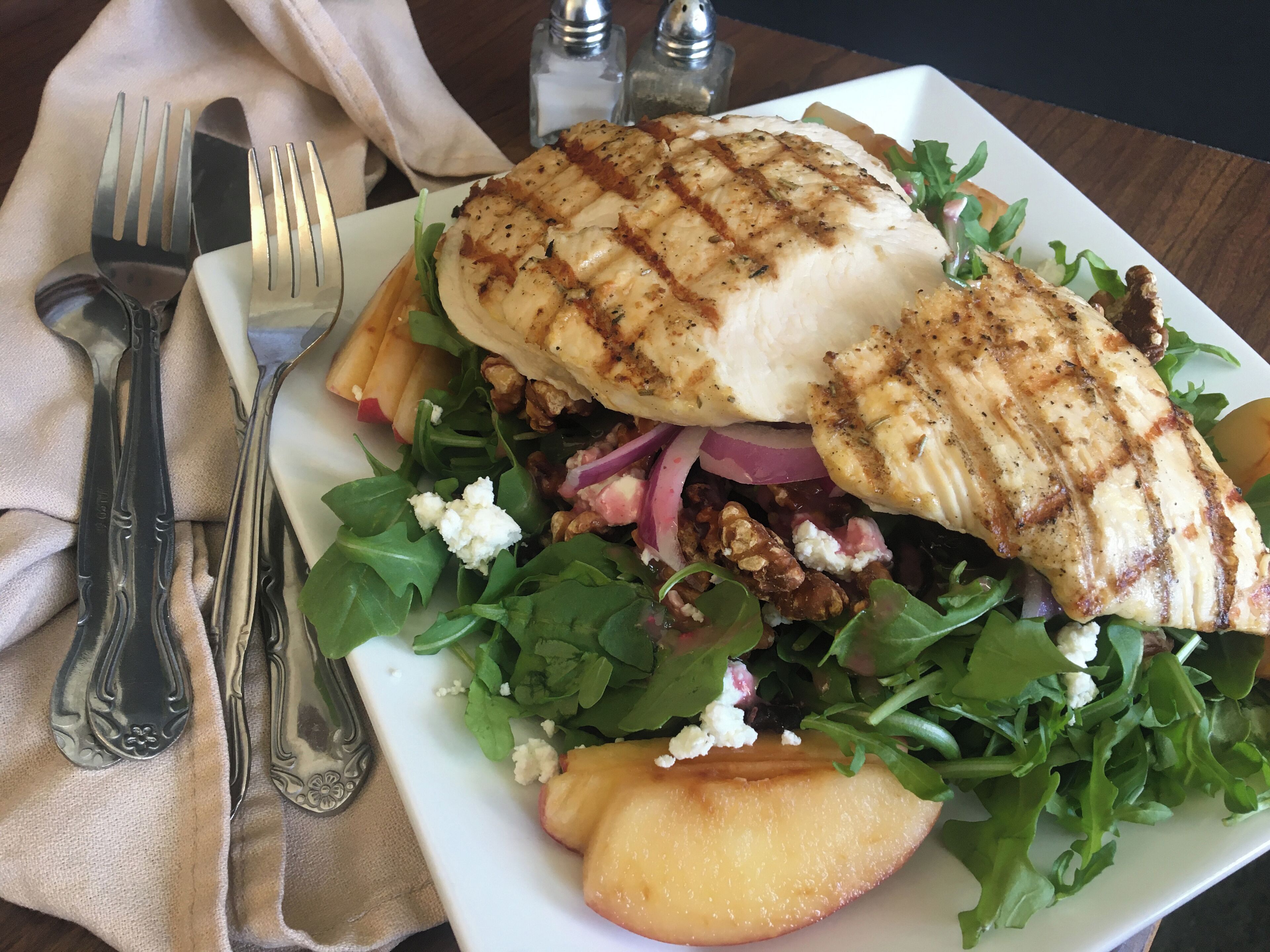 A plate of grilled chicken, mixed greens, and feta cheese.
