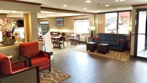 A hotel lobby with a seating area, a reception desk, and a dining area. - Comfort Inn Festus - St Louis South (Festus)