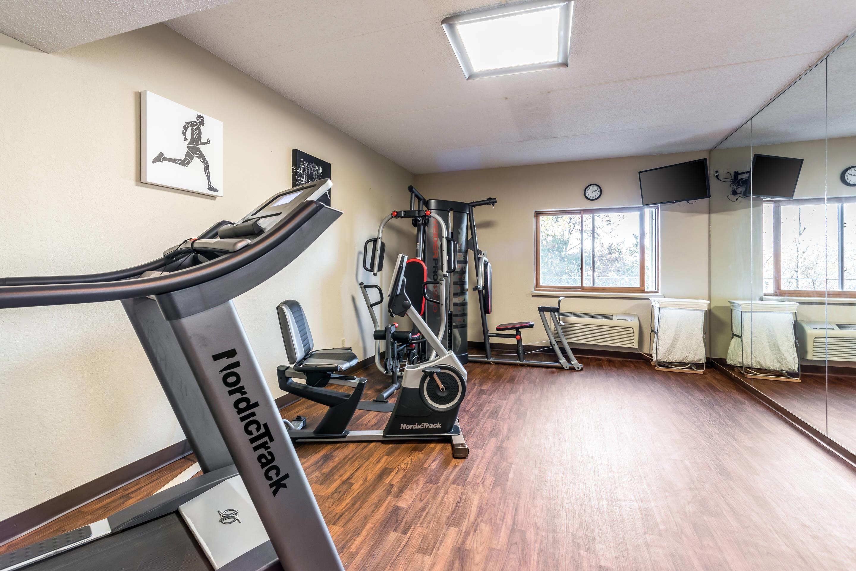 Et fitnesscenter med løbebånd, styrkemaskiner og et spejl.