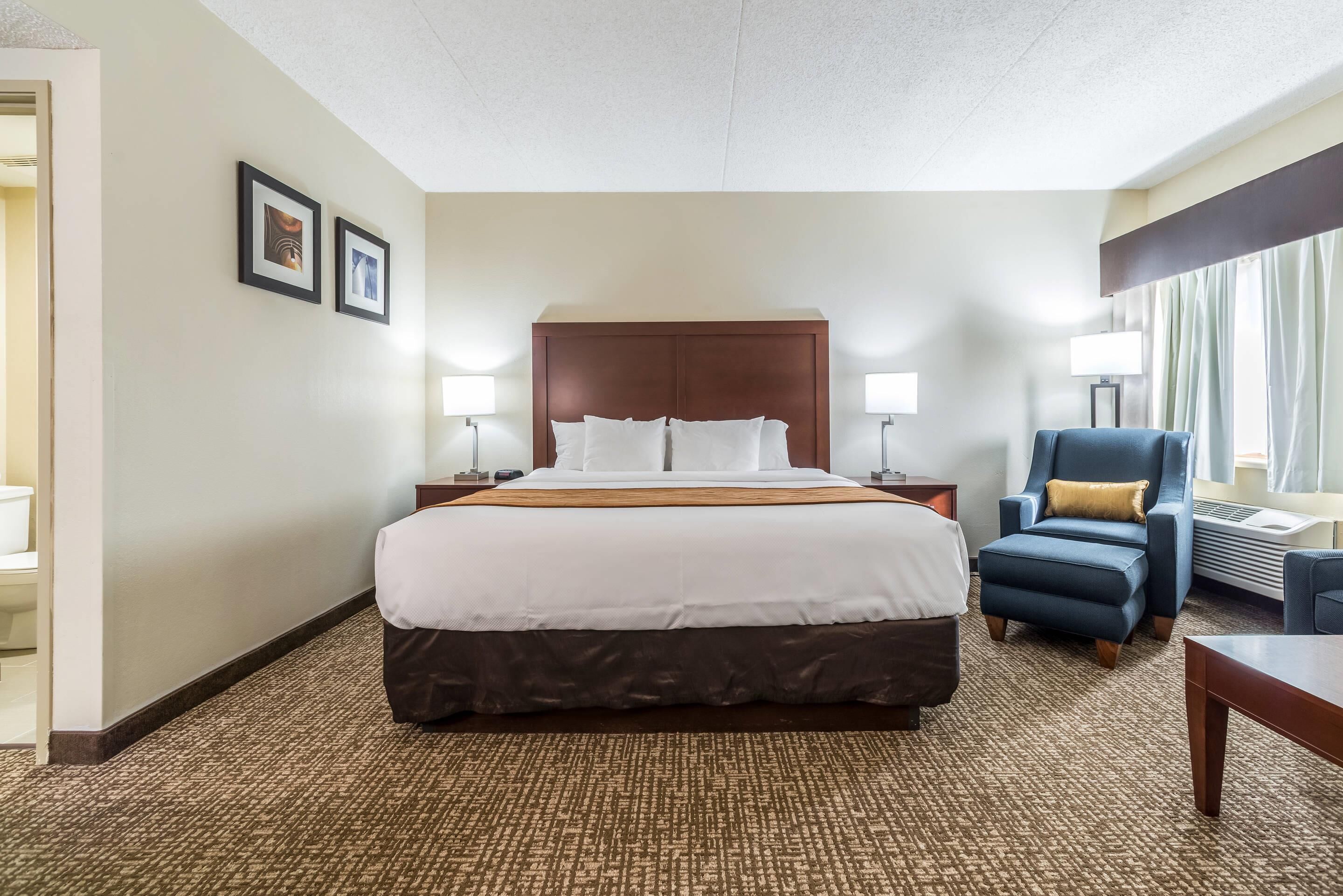 A hotel room with a large bed, two bedside tables, a chair, and a desk.