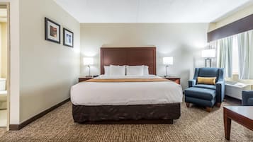 A hotel room with a large bed, two bedside tables, a chair, and a desk.